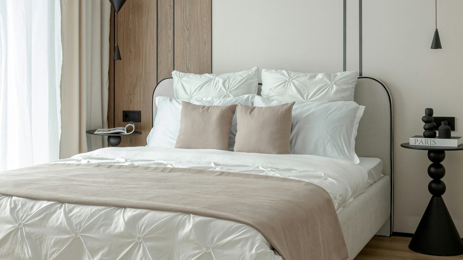 Bright modern bedroom with a neatly made bed, neutral bedding and warm wood flooring