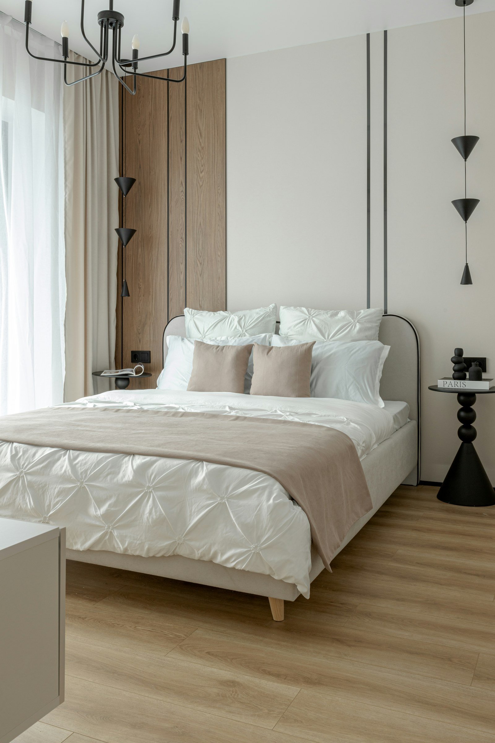 Bright modern bedroom with a neatly made bed, neutral bedding and warm wood flooring