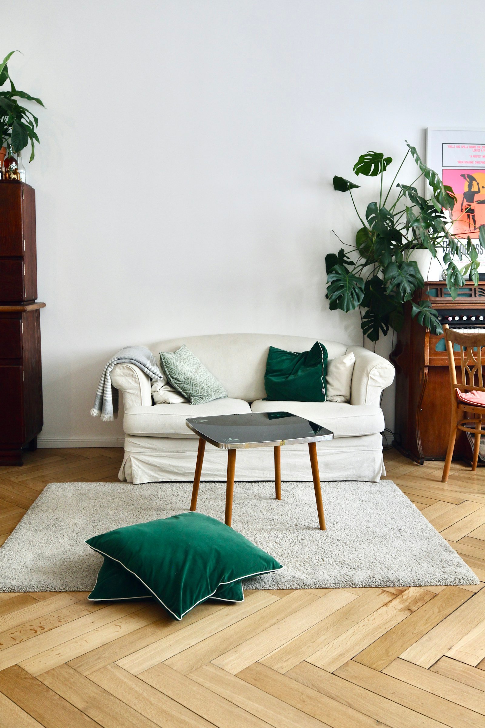 White sofa with layered green and patterned cushions in a calm living room