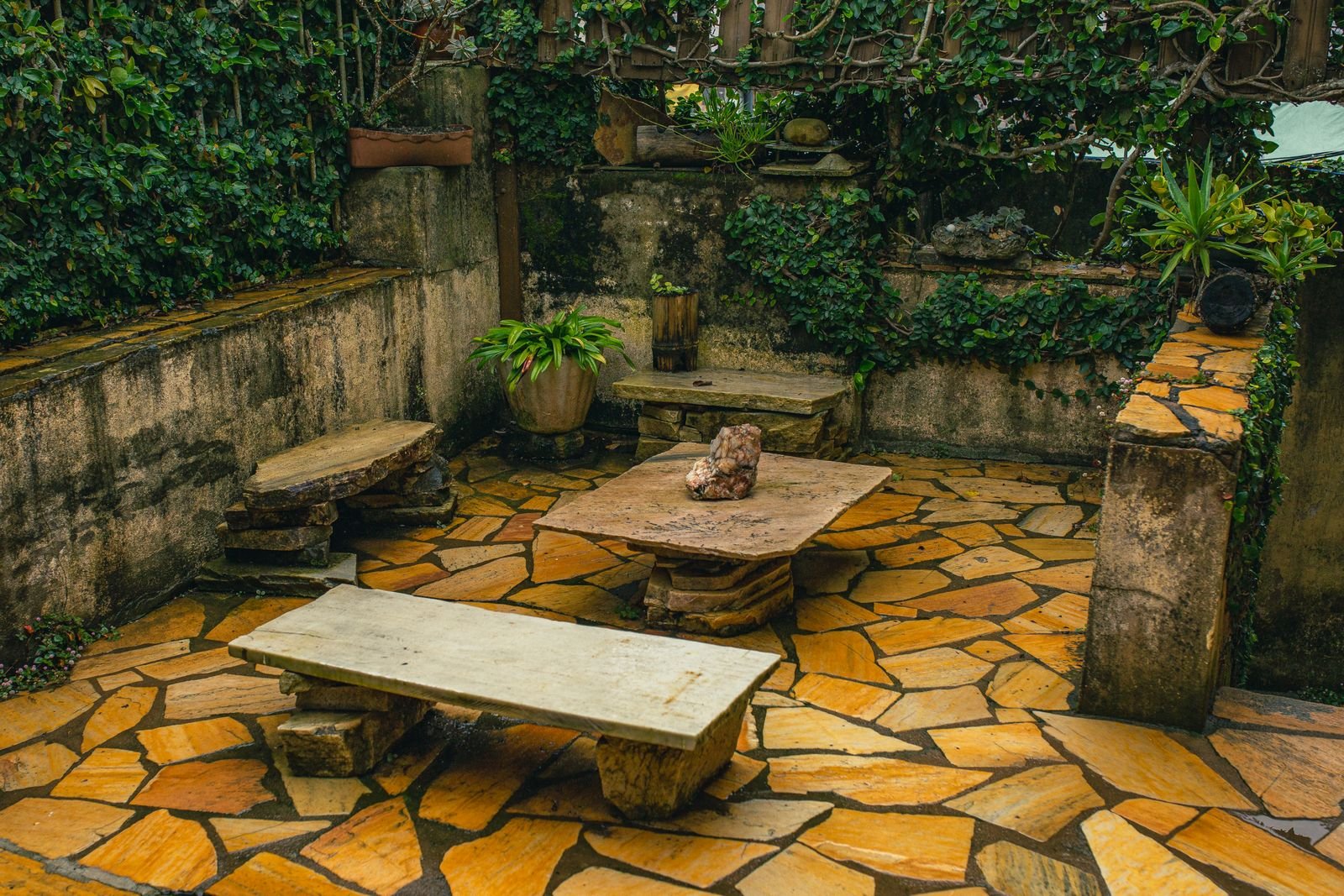 Garden seating on a stone patio beneath an ivy-covered wall