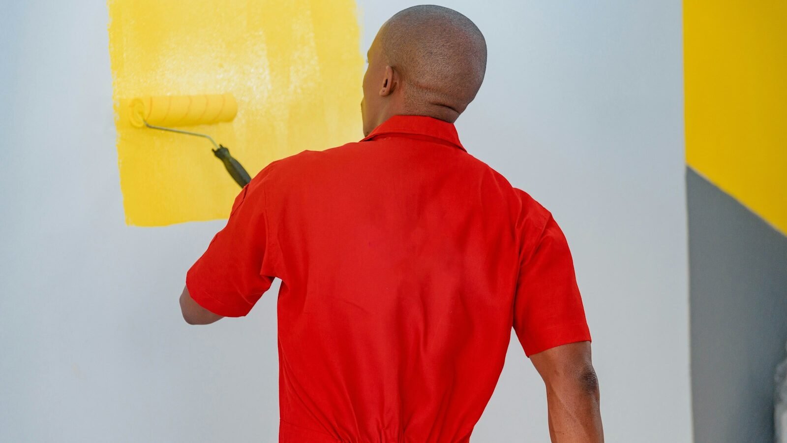 DIY painter applying yellow paint to an interior wall