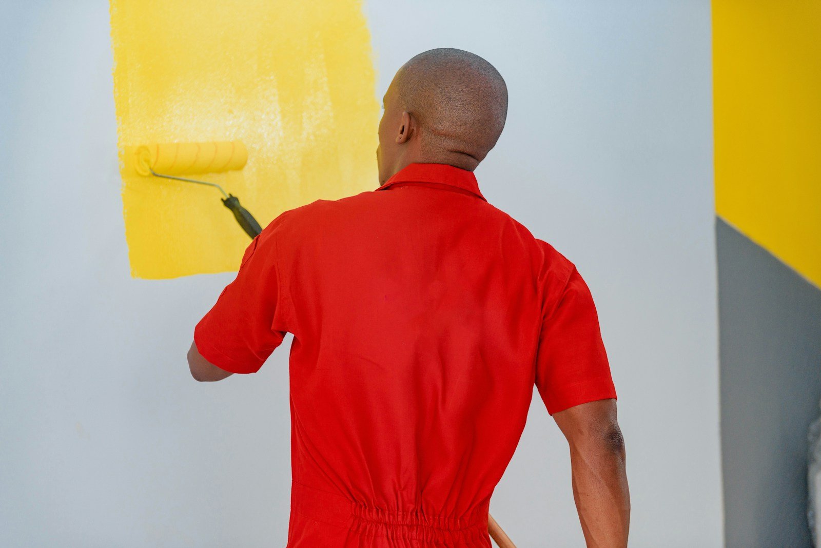 DIY painter applying yellow paint to an interior wall