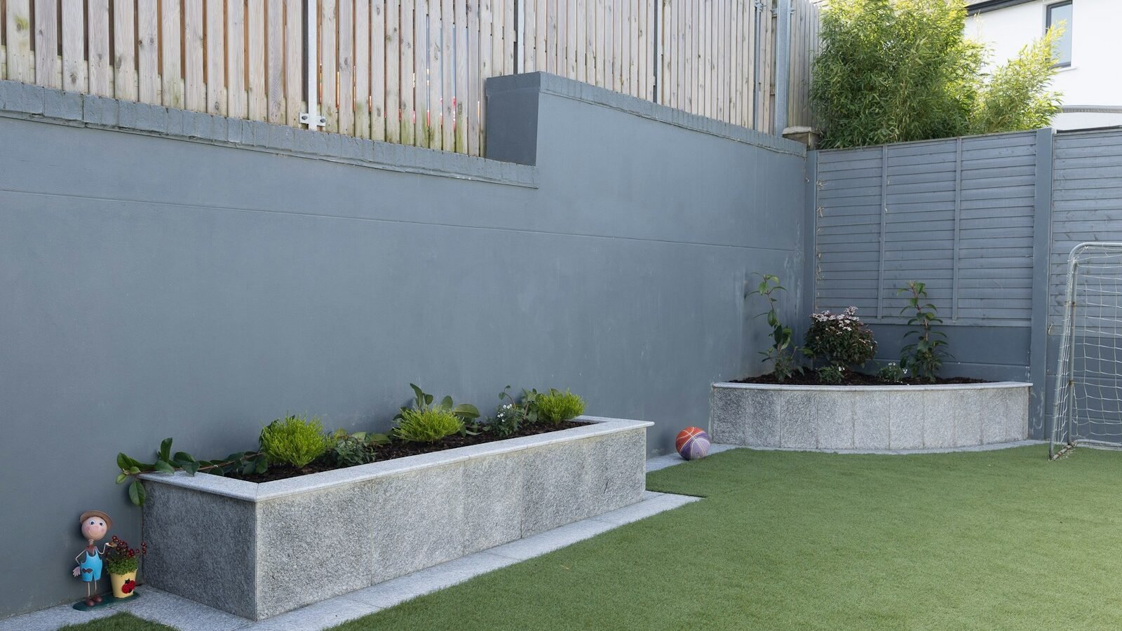 Back garden with lawn, planting beds and a paved seating area