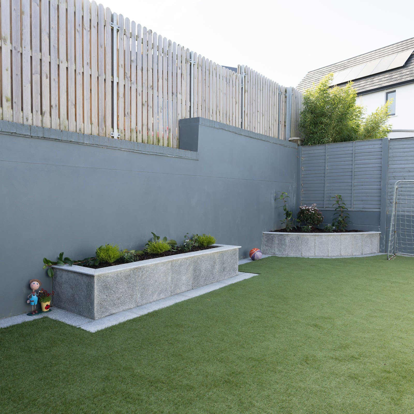 Back garden with lawn, planting beds and a paved seating area