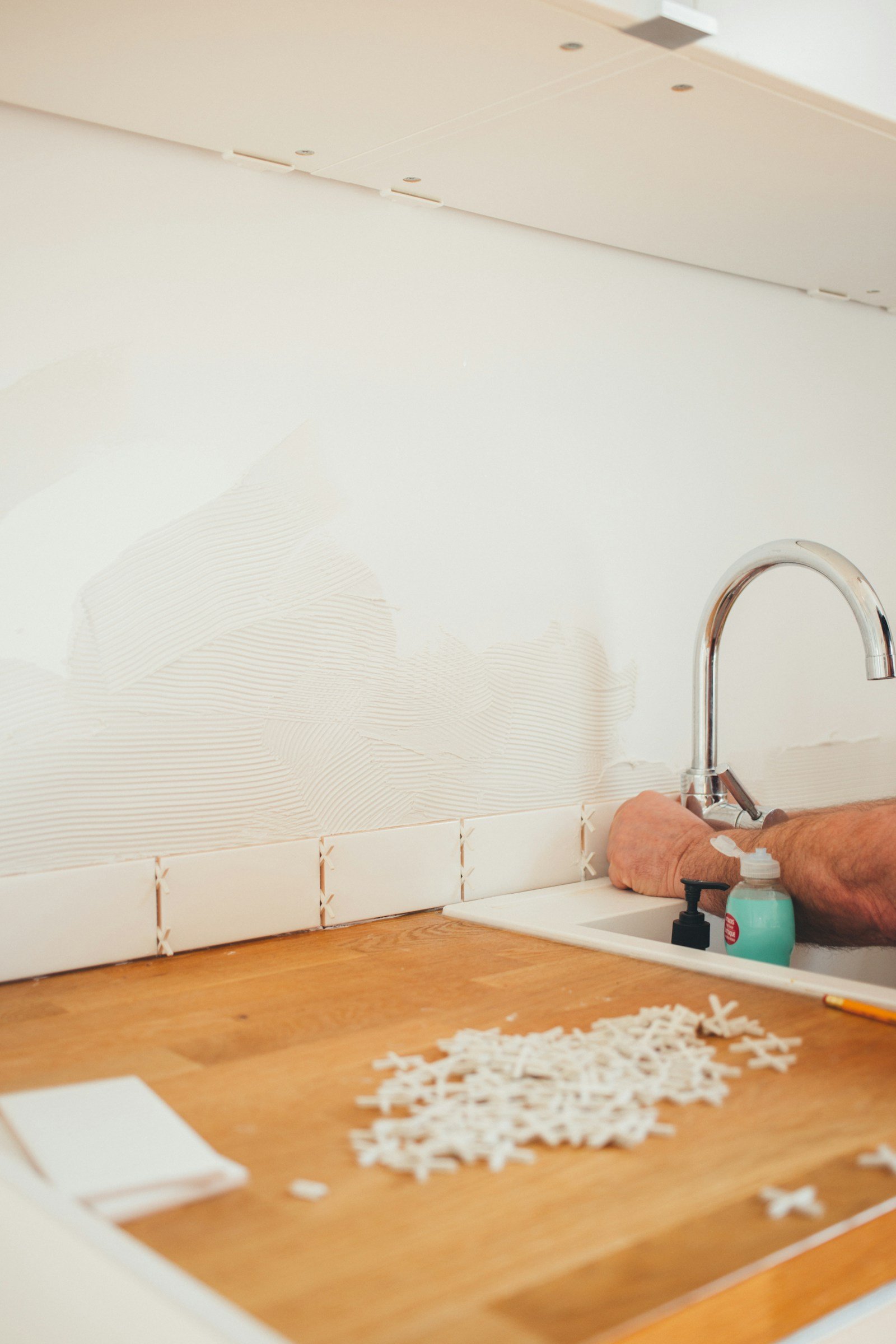 Hands holding a chrome faucet during a DIY plumbing repair