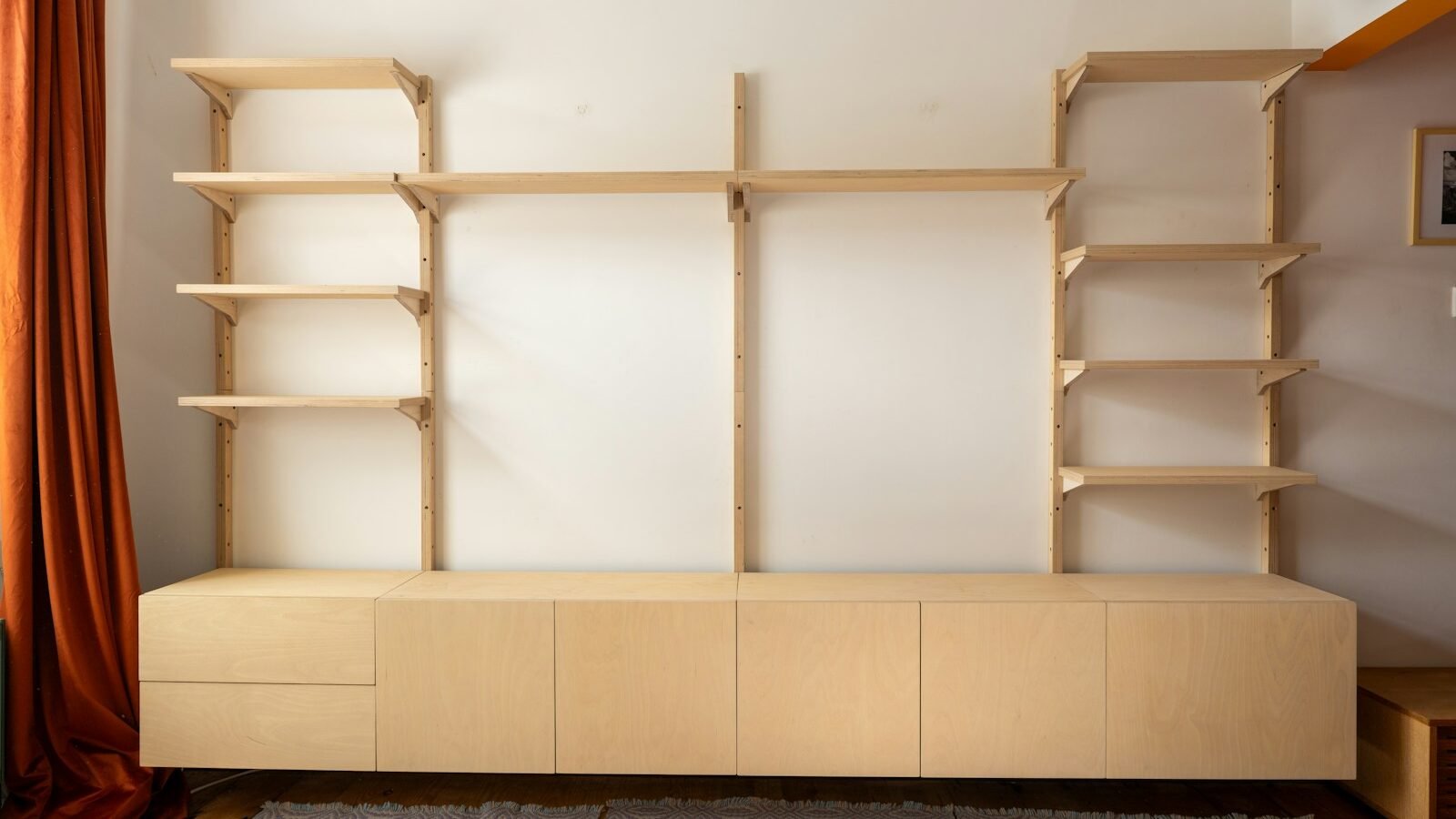 Light wood storage wall unit with open shelving and cupboards