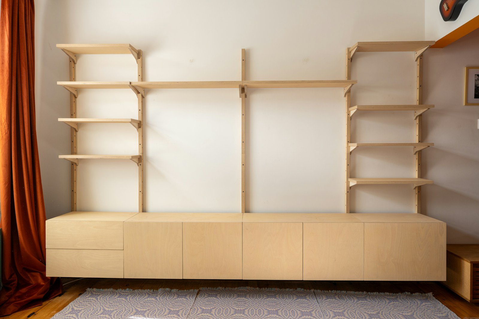 Light wood storage wall unit with open shelving and cupboards