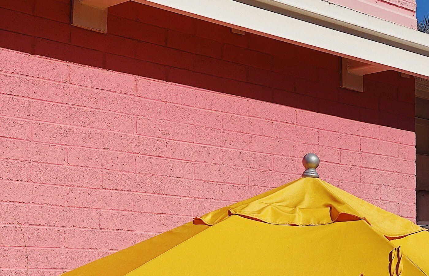 Red patio umbrella beside a brick garden wall