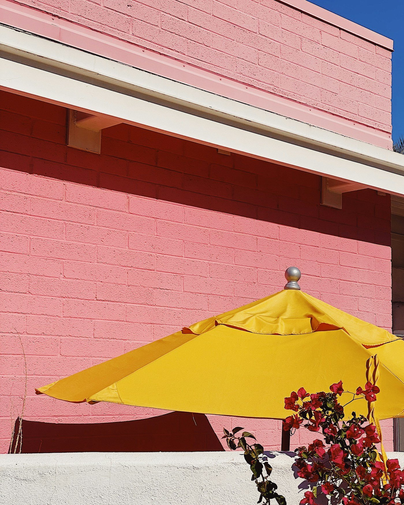 Red patio umbrella beside a brick garden wall