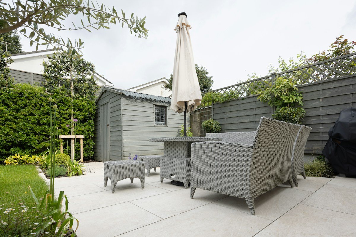 Low-maintenance patio garden with paved terrace, outdoor seating, and evergreen planting