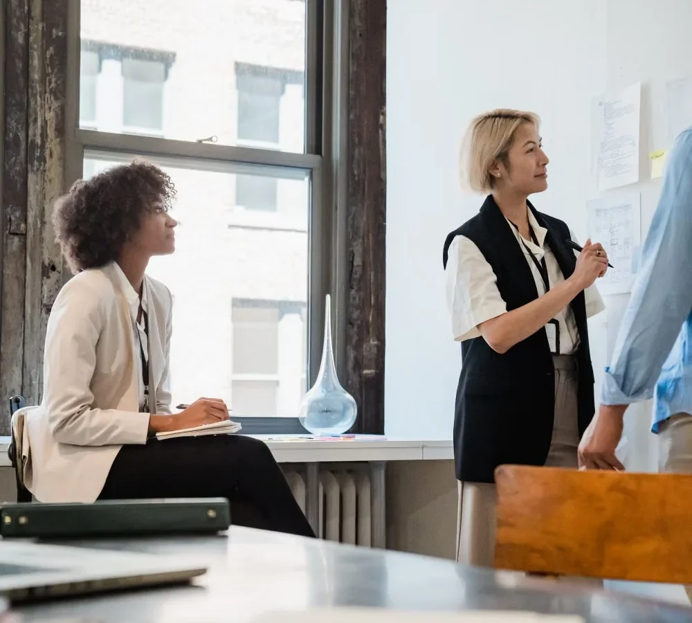 Colleagues planning corporate office interior design around a table in a bright office