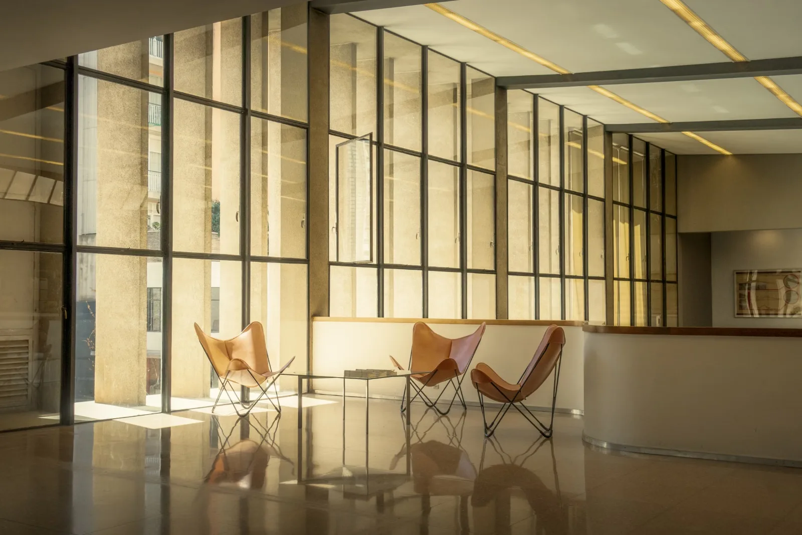 Lounge chairs and a low table beside full-height office windows