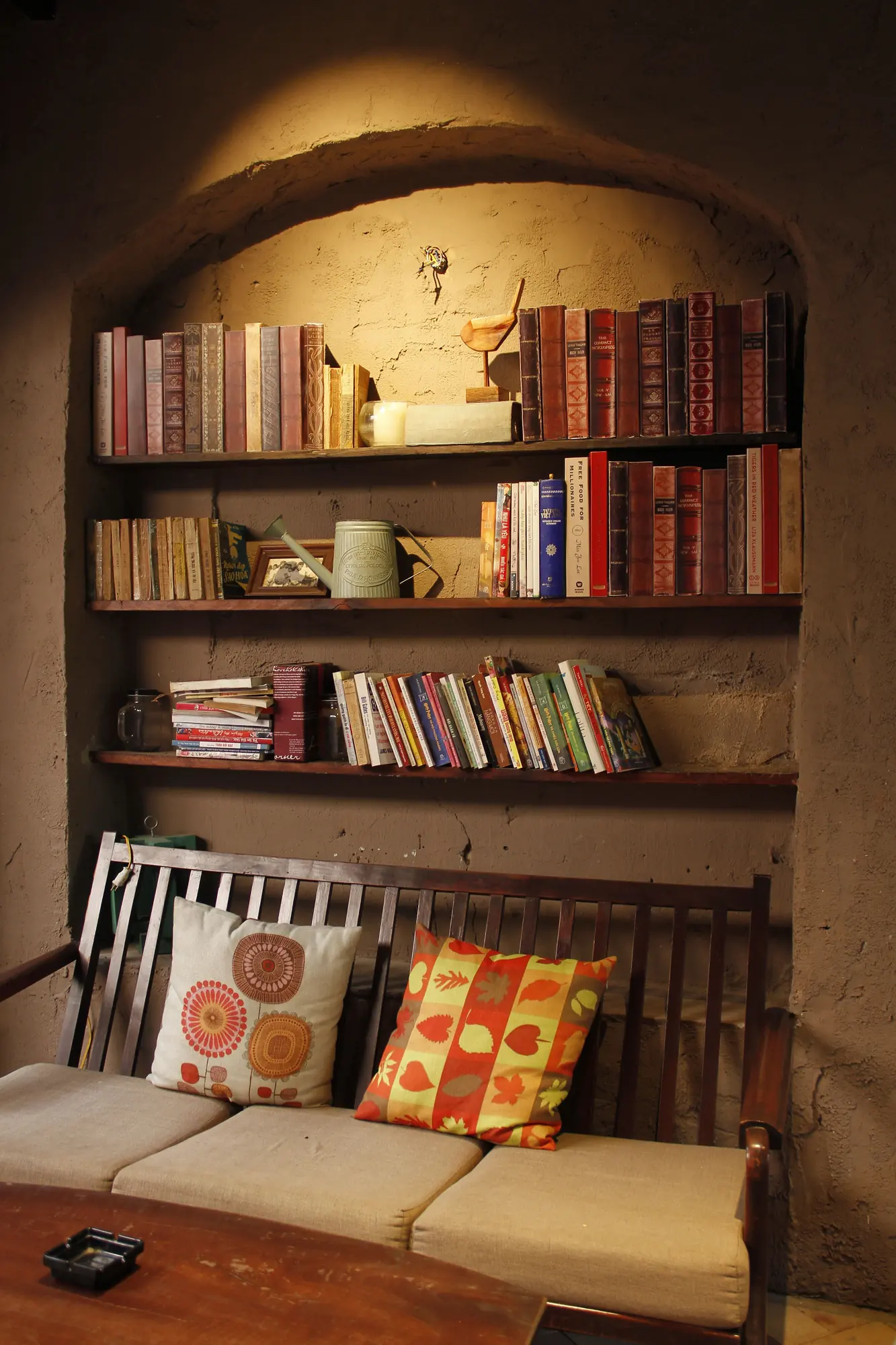 Bookshelves above a cushioned bench in a warm reading corner