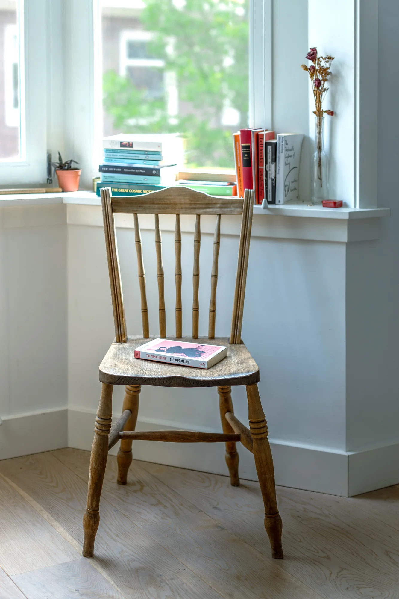 Wooden chair with a book beside a bright window