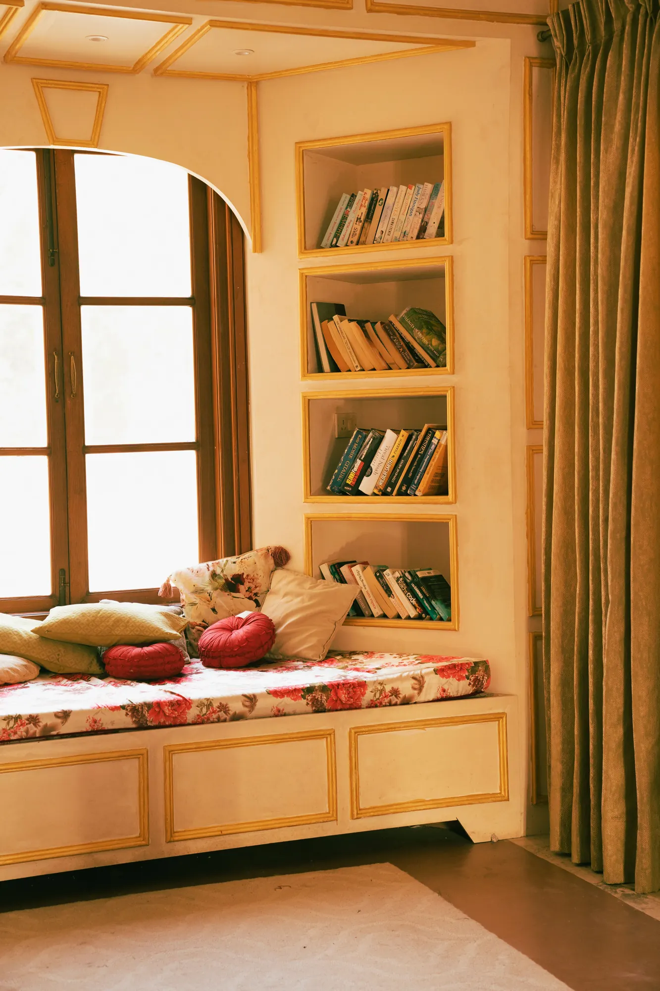 Cushioned window seat with bookshelves beside a tall window